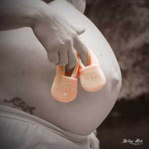 Catégorie Maternité - femme enceinte avec chausson de bébé rose en extérieur